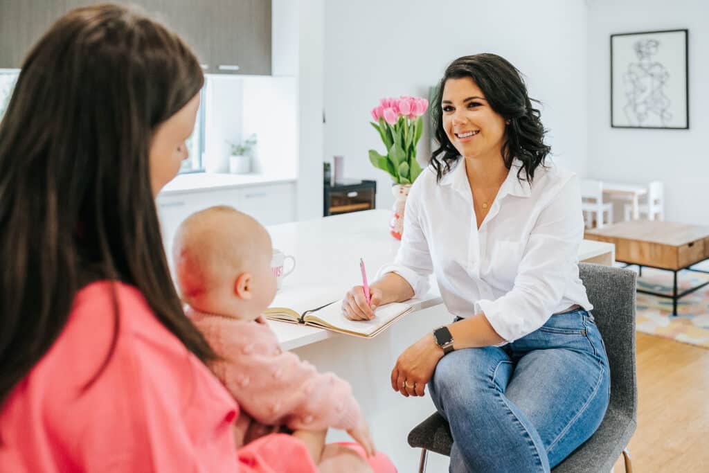 Andrea Bombino at Made to Mother Co works as a Motherhood & career coach, listening to a client who holds a baby.