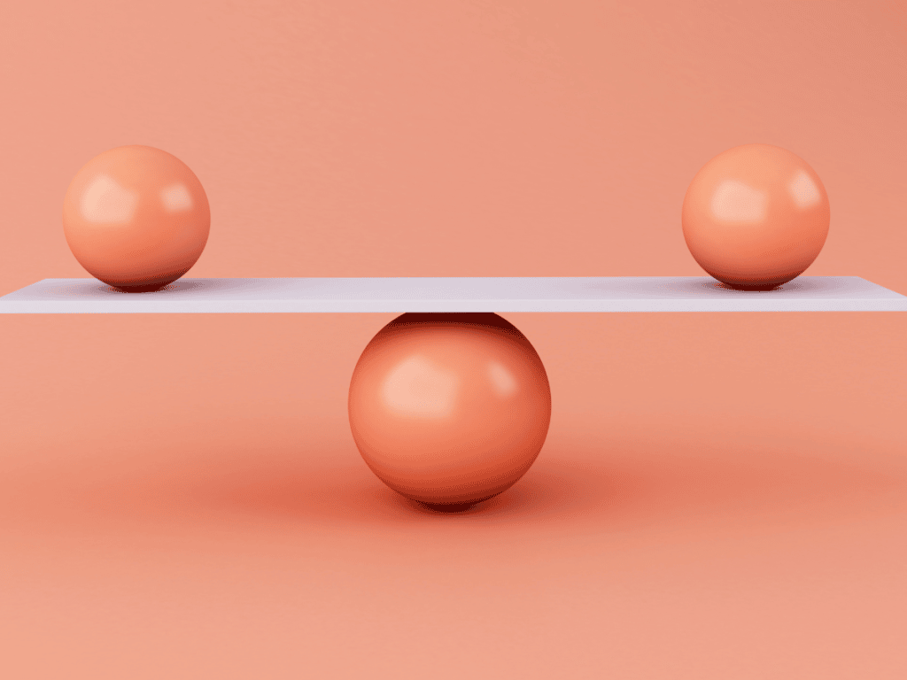 Two balls balance on a board, which balances on a larger ball, representing a seesaw. Made to Mother Co's Andrea Bombino explains that it's difficult to create a true work-life balance for moms, when in reality, we often place more weight on some things than others (such as with a seesaw).